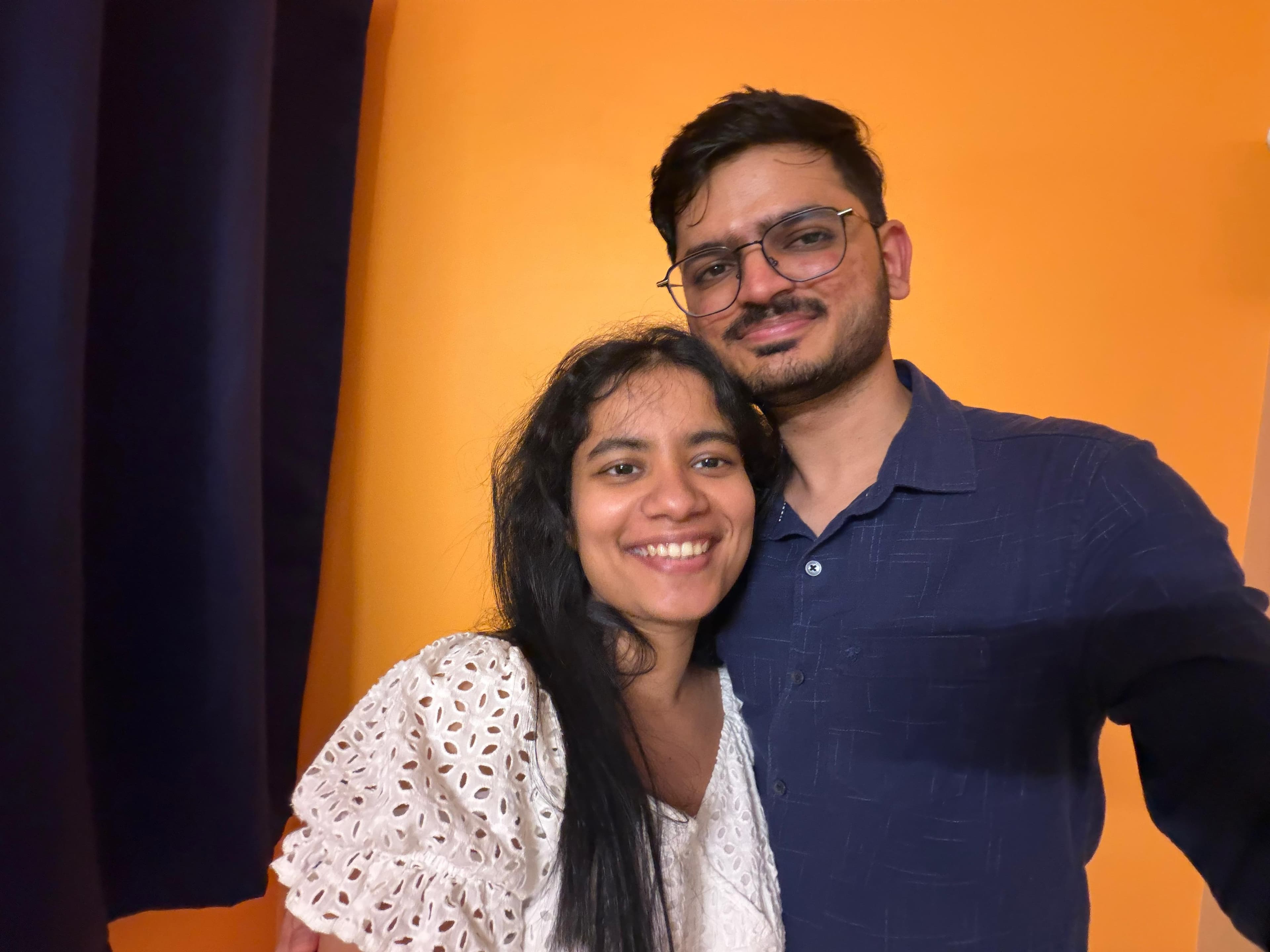 the two of us smiling in a selfie against an orange wall